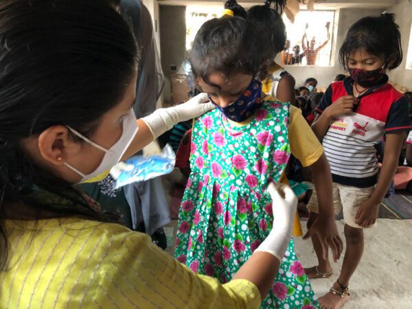 A woman in yellow shirt putting on face mask.