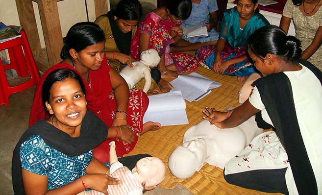 A group of women sitting on the floor making paper mache.