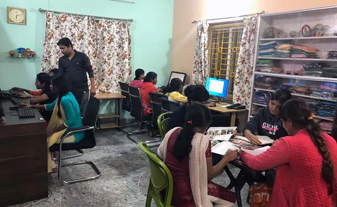A group of people sitting around in front of computers.