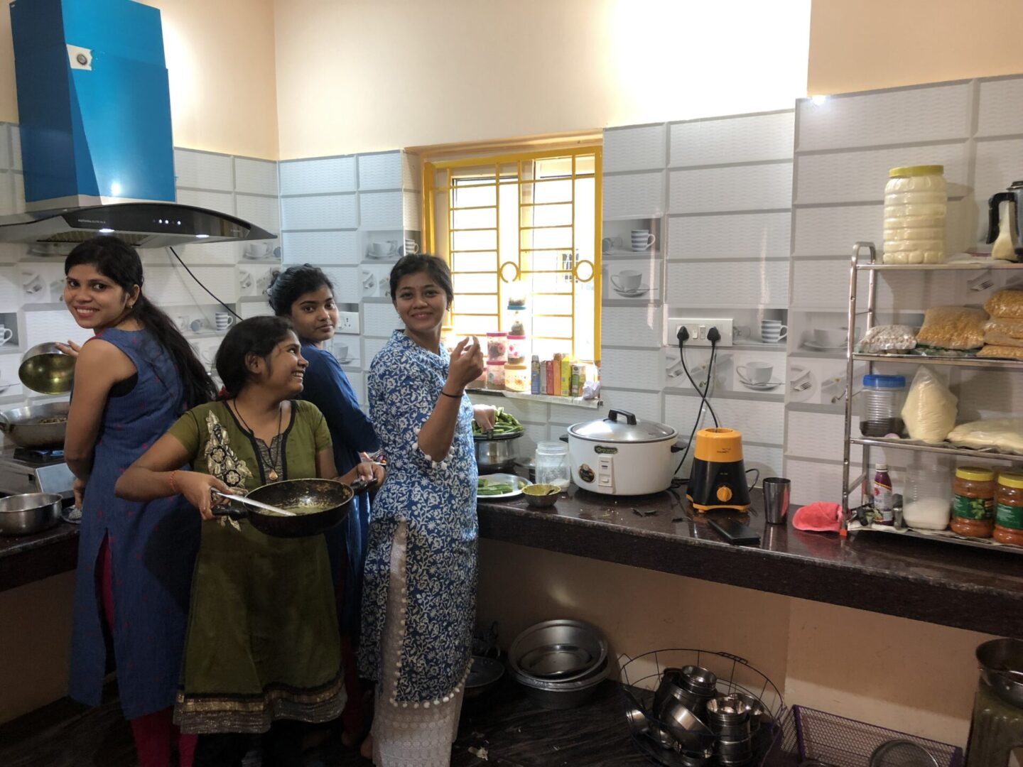 A group of people standing around in a kitchen.