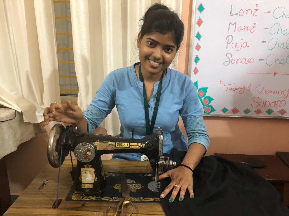 A woman sitting in front of an old sewing machine.