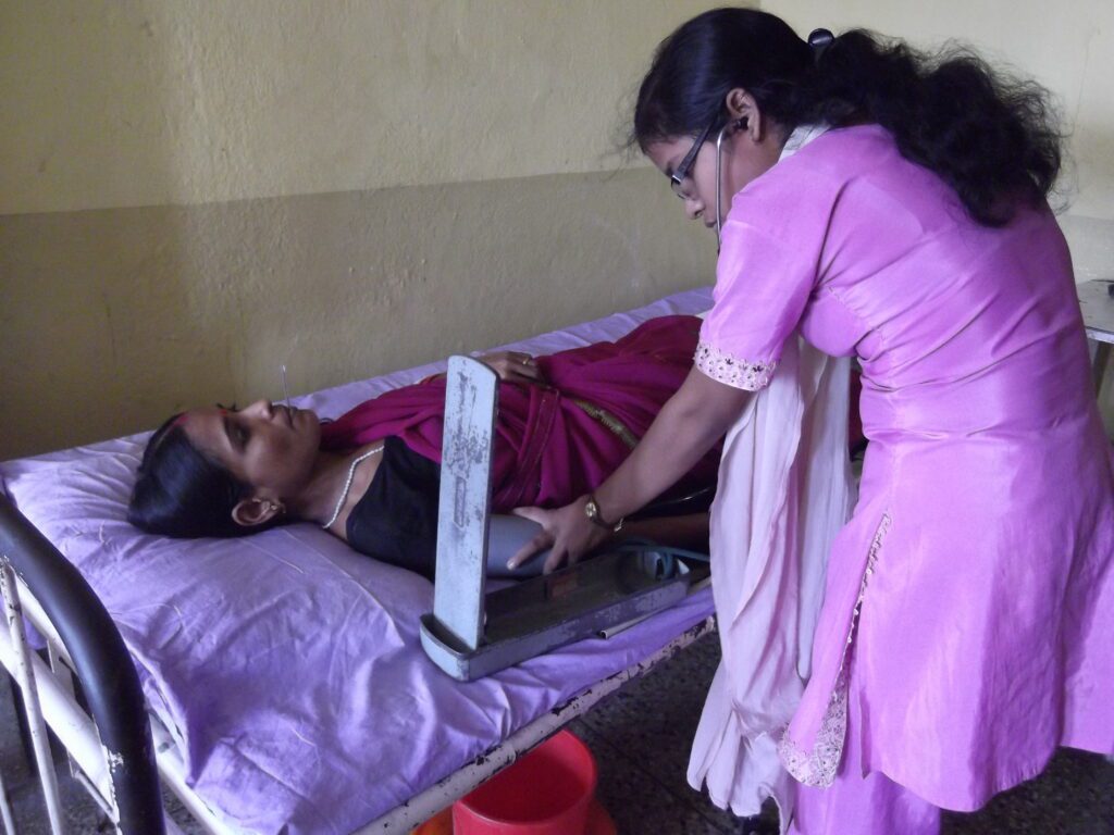 A woman helping someone in bed with a laptop.