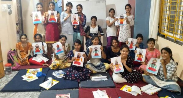 Group of children proudly displaying their artwork in a classroom setting.