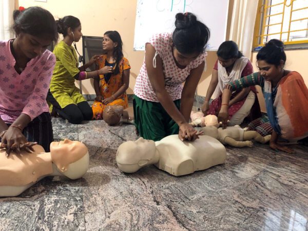 Group practicing CPR on mannequins indoors.