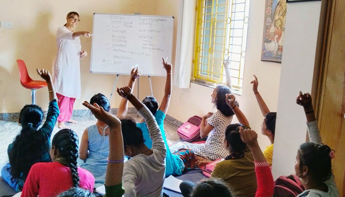 Children enthusiastically raise hands in a classroom setting.