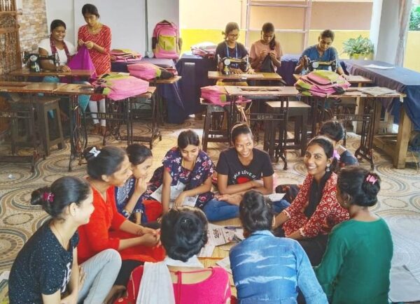 A group of women sitting and engaging in a lively discussion indoors.