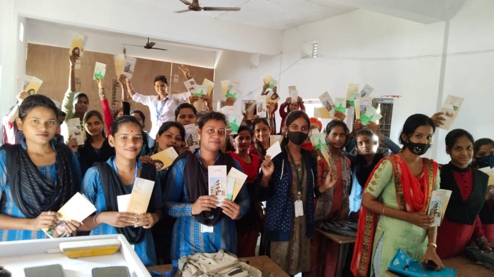 A group of women happily holding up books in a classroom.