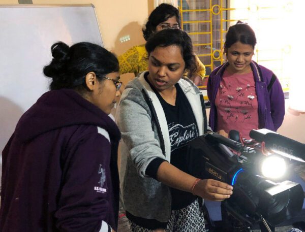 Three women engaged in a hands-on technical activity with equipment.