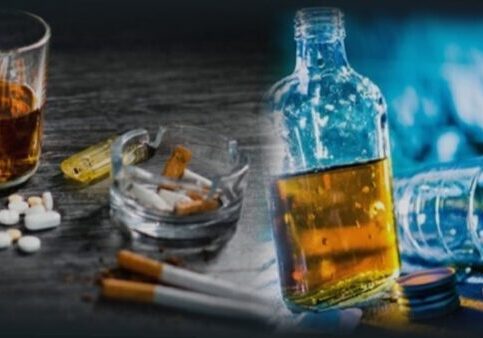 A glass bottle of alcohol and cigarettes on the table.