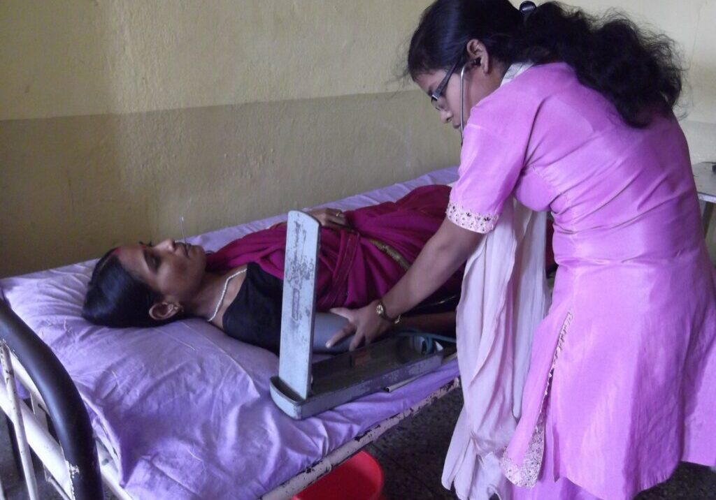 A woman helping someone in bed with a laptop.